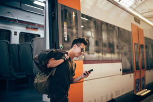 Handsome young Chinese commuter waiting for a train at the train station.